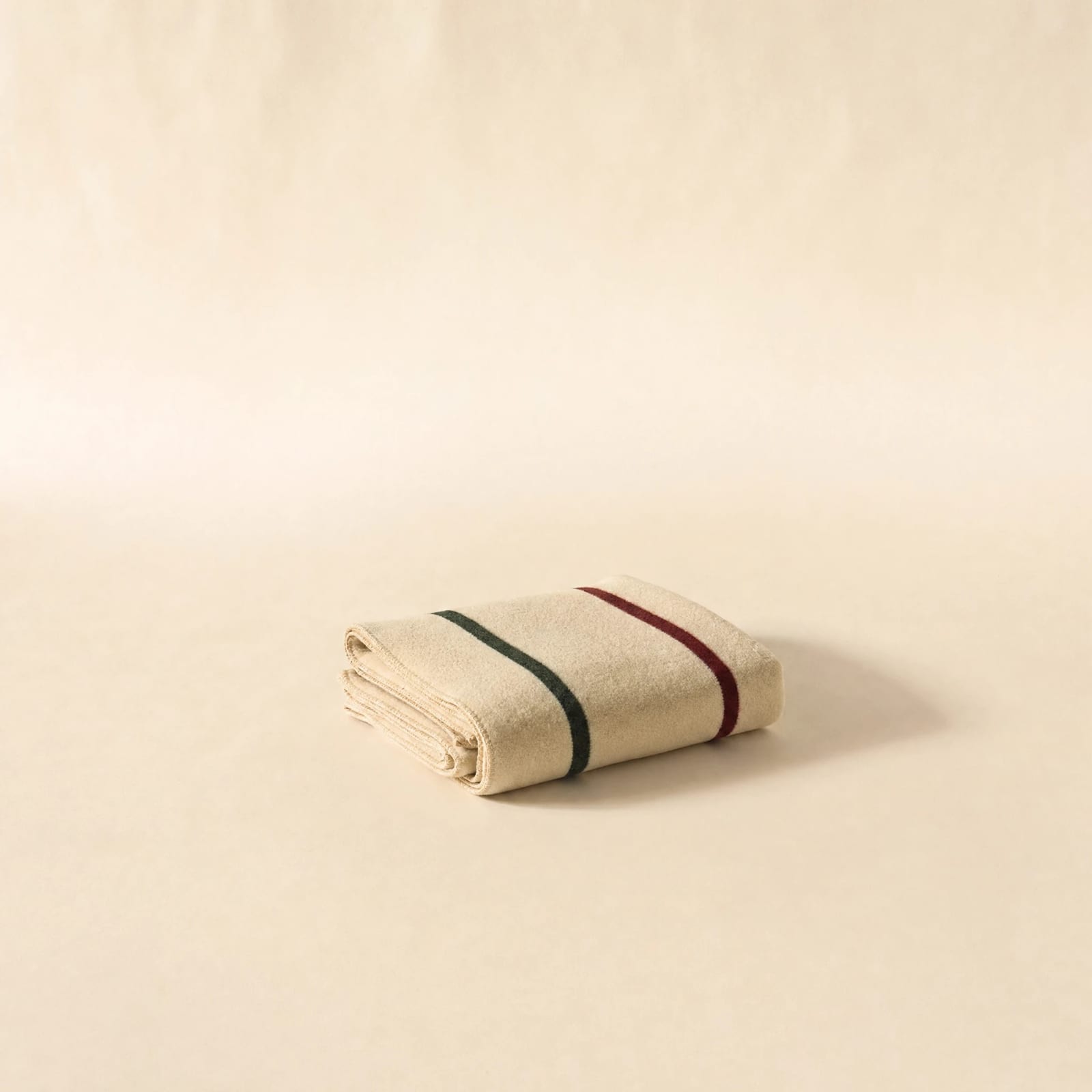 No. 02 Camp Blanket — folded cream merino wool with burgundy and forest-green point stripes